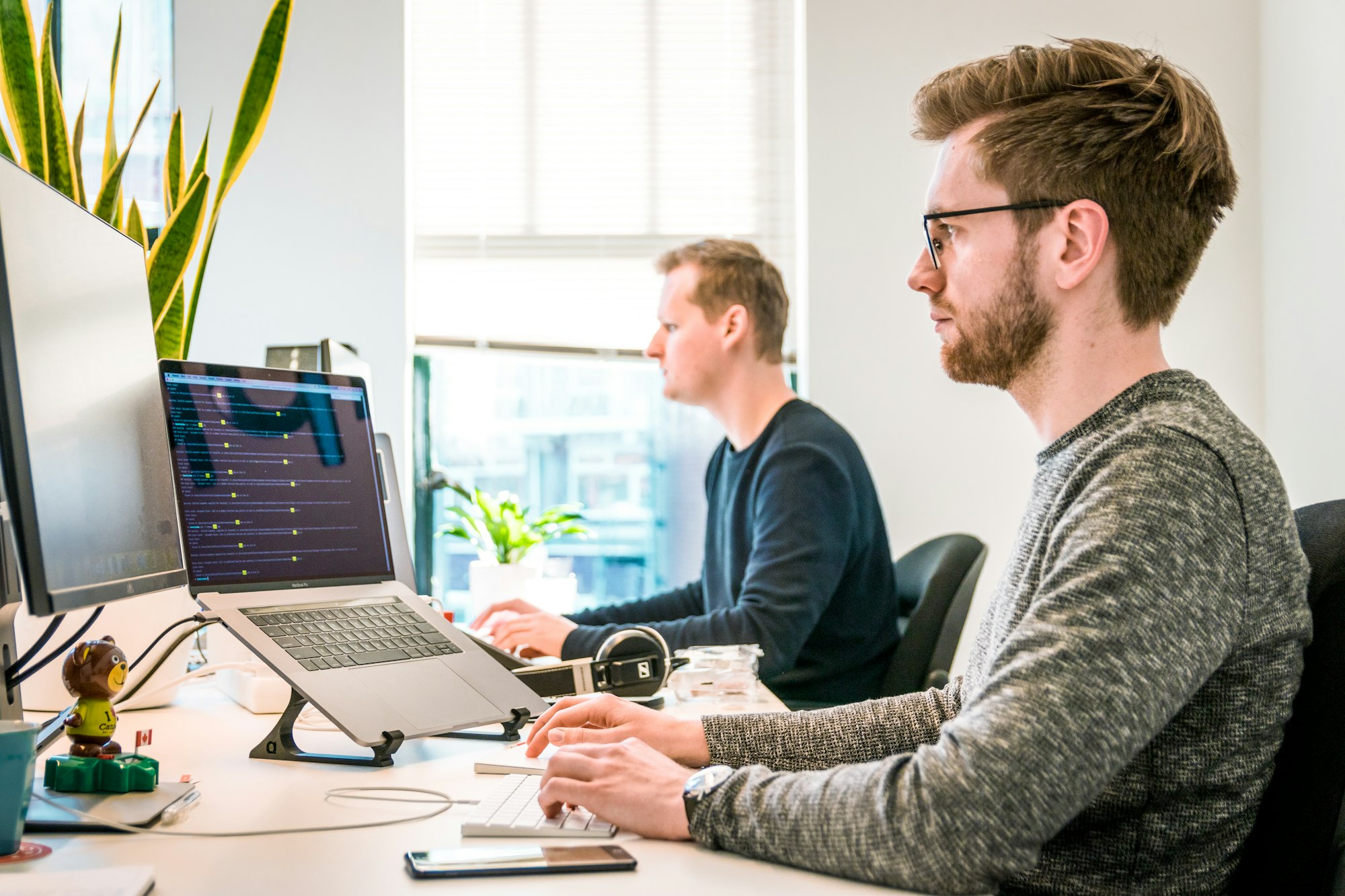 Two collaborators reviewing a software interface on a laptop